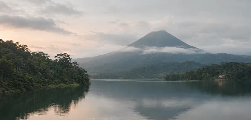 A volcano above rainforest and a still lake at dawn, Costa Rica